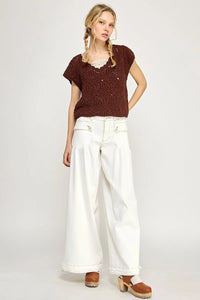 Woman in brown knit top and white wide-leg pants from Shop Daisy’s women’s boho chic clothing