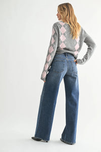 Woman wearing high rise bohemian wide leg denim jeans and gray argyle sweater