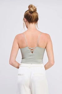 Woman wearing a green smooth rib bralette tank with laser cut back detail