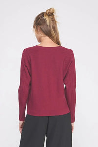 Woman wearing a fine gauge boat neck sweater in maroon with black pants