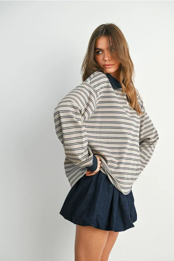 Woman wearing a striped collared long sleeve polo shirt paired with a dark mini skirt