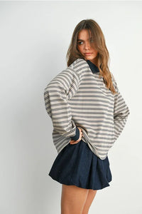 Woman wearing a striped collared long sleeve polo shirt paired with a dark mini skirt