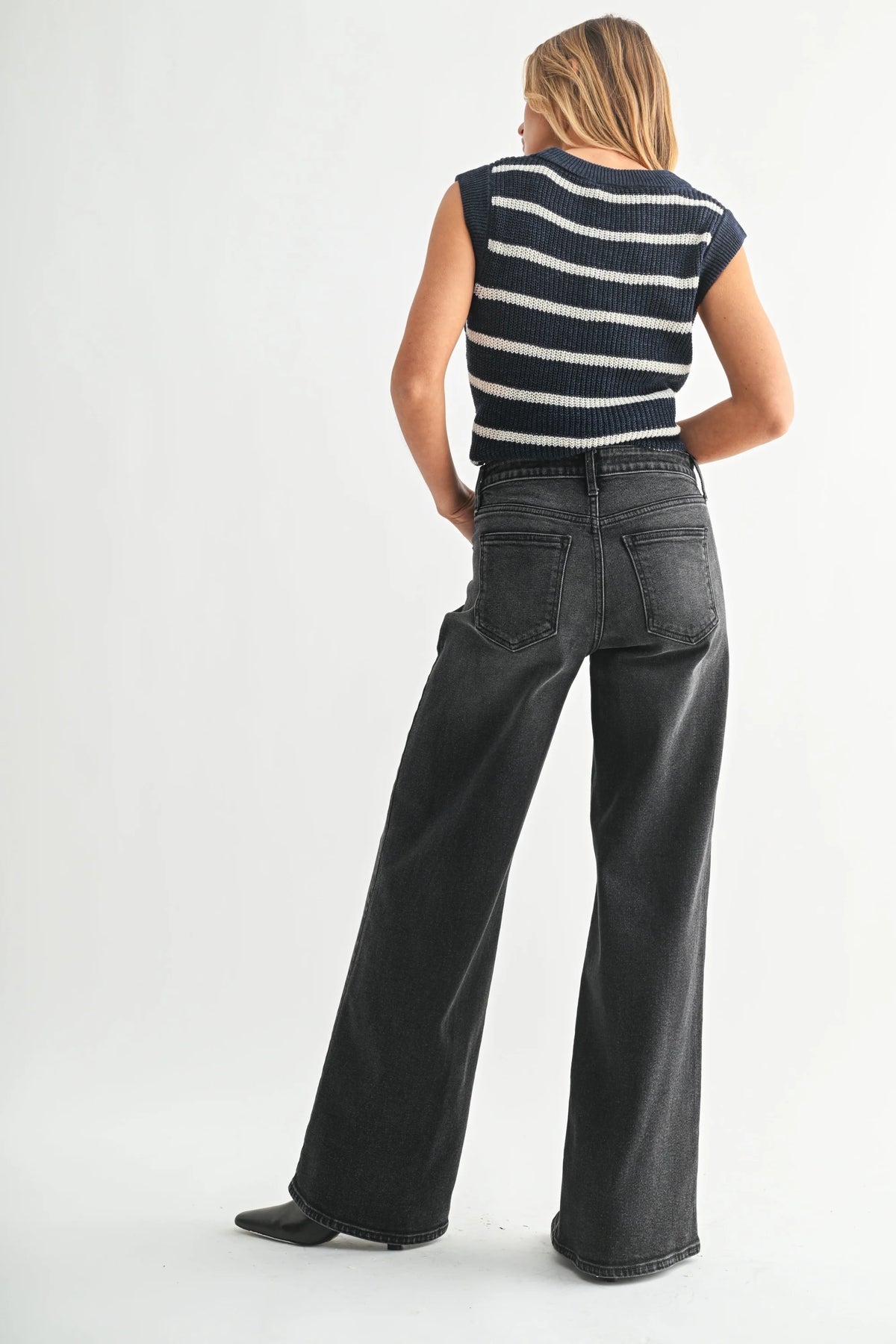 Woman wearing high-rise bohemian wide-leg denim jeans and striped sleeveless sweater