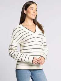 Women’s cream-colored V-neck sweater with black stripes, part of the Supply IRA collection