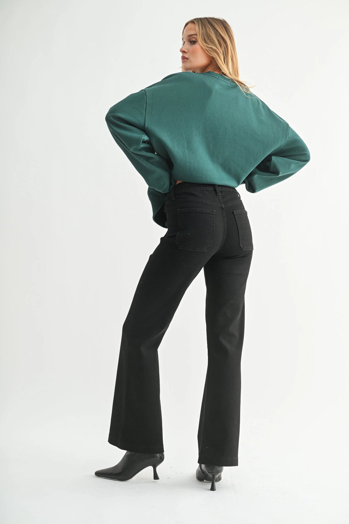 Women’s dark teal long-sleeve top with black patch pocket flare jeans and high heels