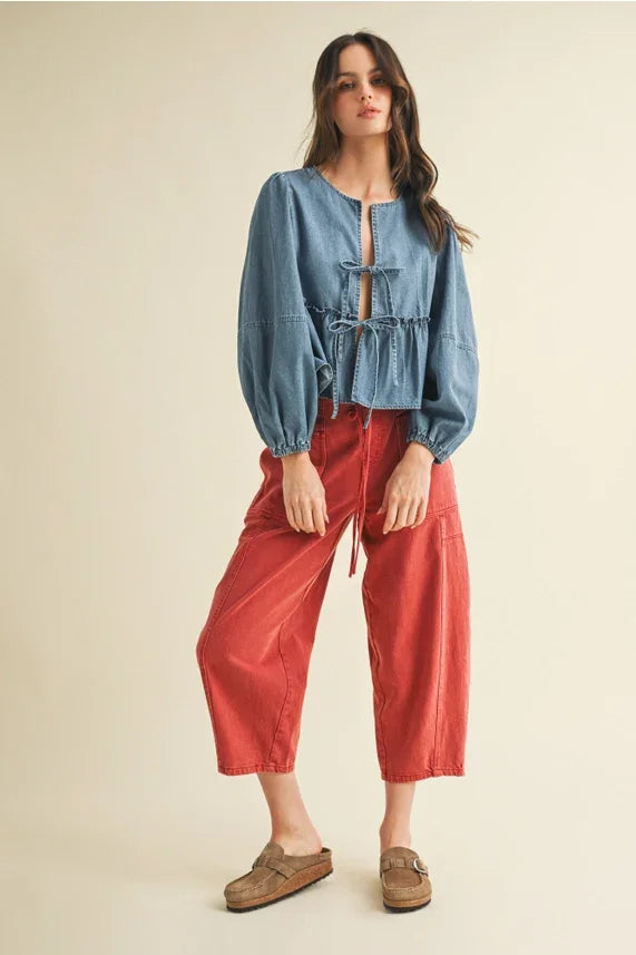 Women’s light blue denim peasant top with ruffle hem and tie closure styling