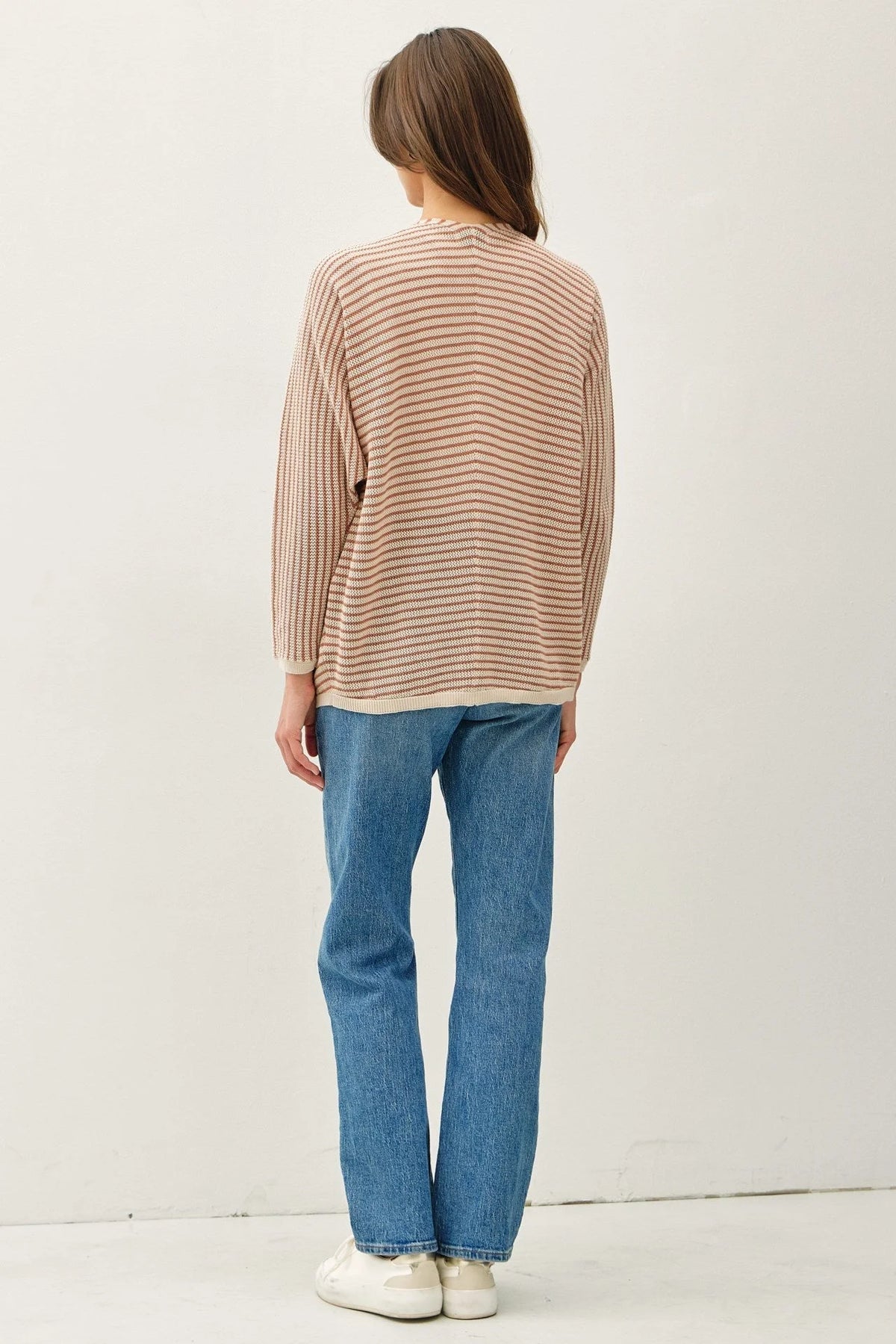 Women’s striped dolman sleeve open cardigan with light and dark brown stripes, blue jeans and white sneakers