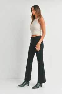 White ribbed crop top with black flare denim jeans and black boots for a stylish look