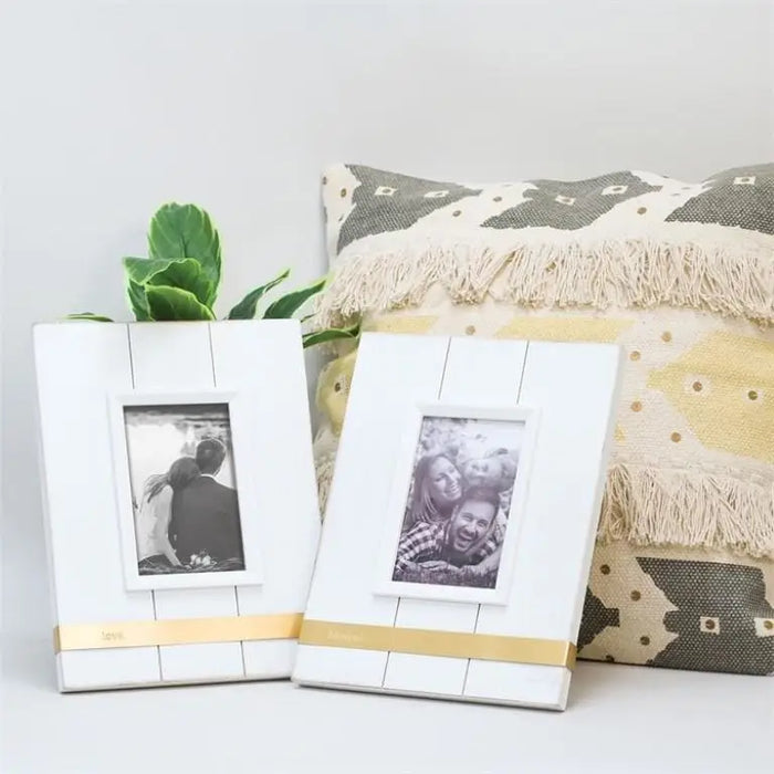 Two white wooden picture frames with yellow accents showcasing black and white photographs.