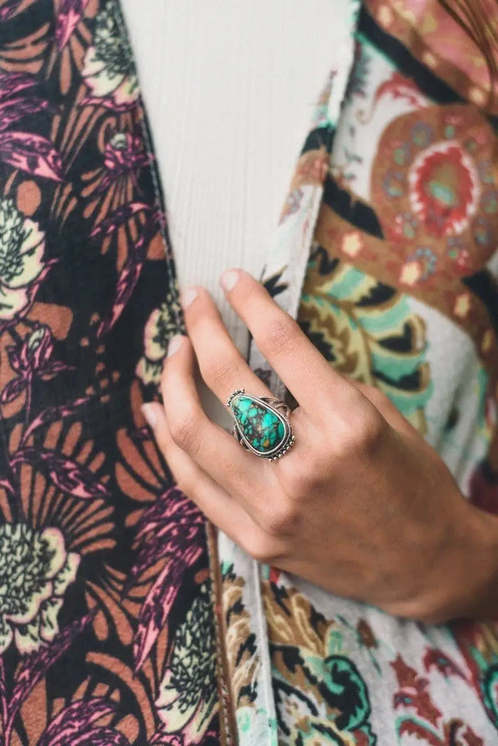 Turquoise gemstone ring on a hand, embodying Boho style against Daisy Lane fabric.
