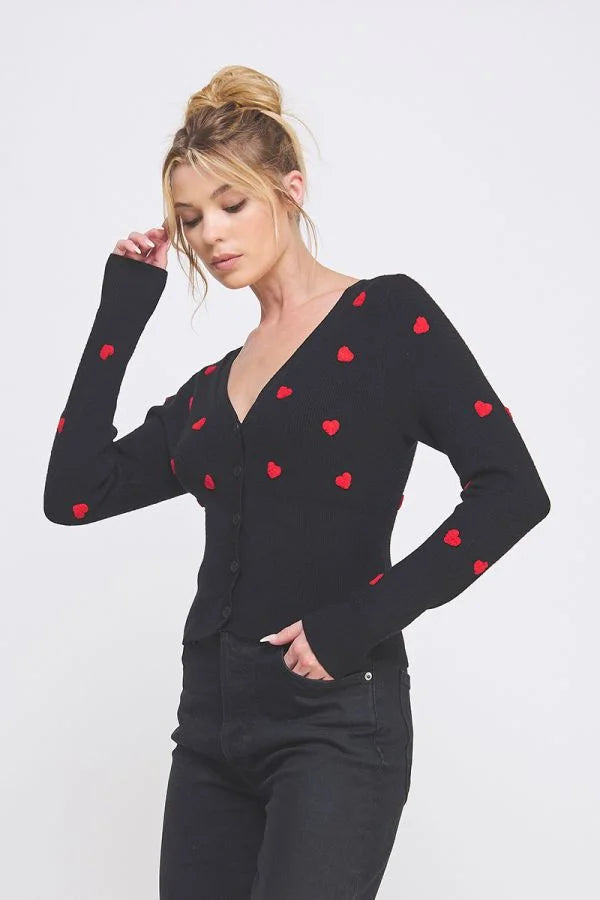 Black cardigan with red hearts, perfect for Valentine’s Day outfit ideas.