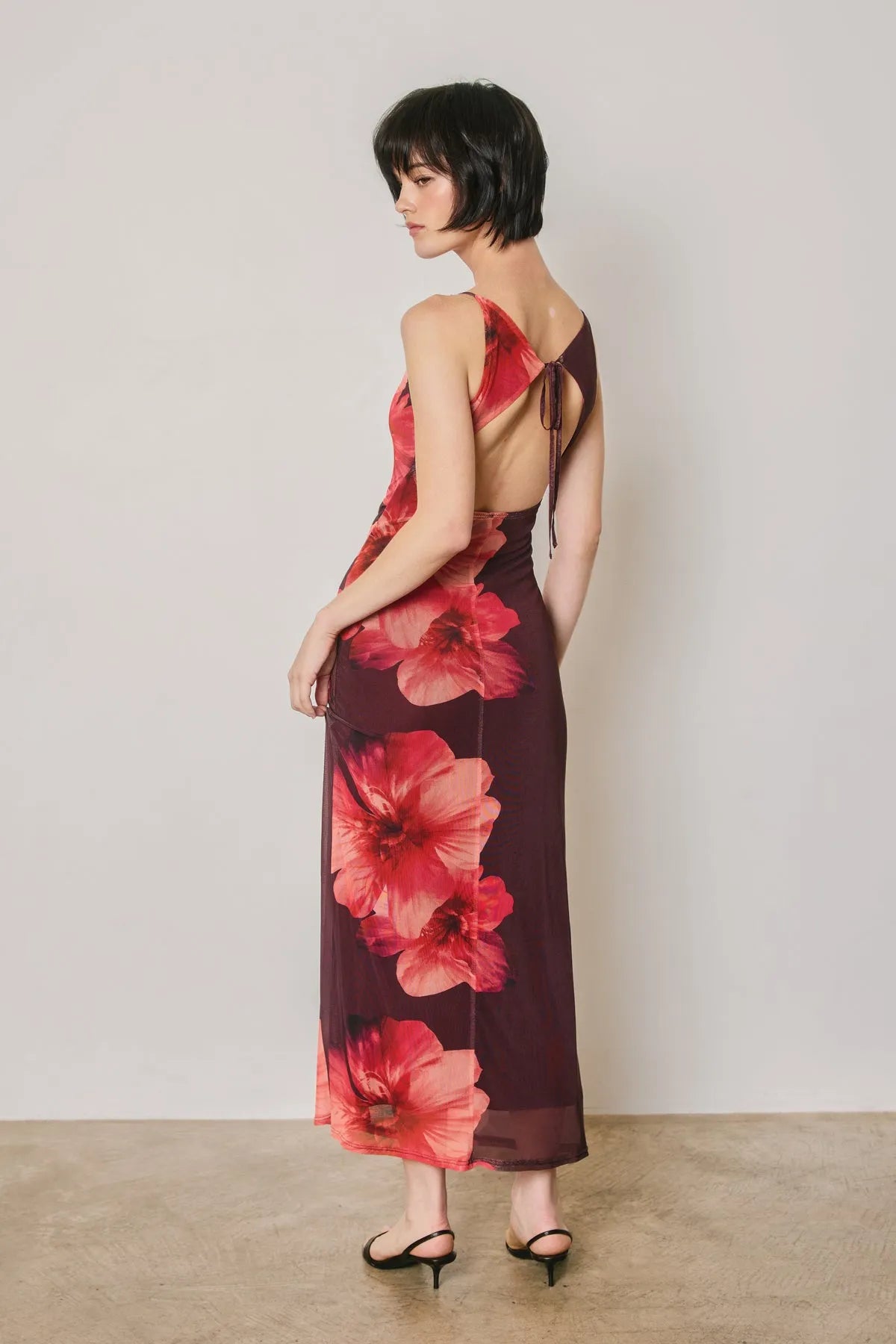 A flowing deep burgundy floral mesh open back maxi dress with red floral prints and sheer overlay