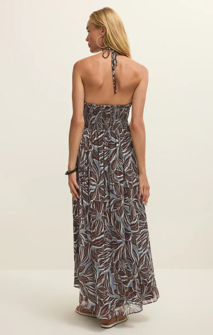 A flowing backless lanie zinn floral maxi dress in dark gray and white leaf pattern with a gathered waistband
