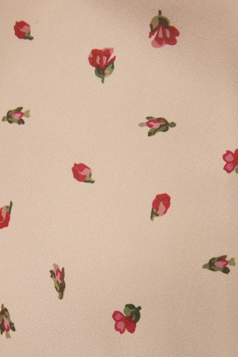 Beige fabric with small red roses and green stems on a ruched bust floral midi dress with spaghetti straps