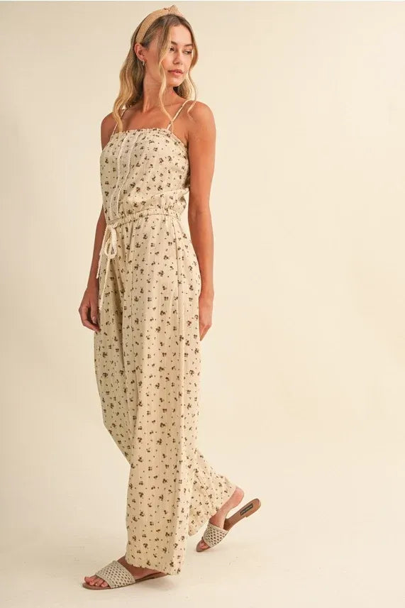 Beige ditsy floral sleeveless jumpsuit with thin spaghetti straps and drawstring waist featuring lace edge barrel design