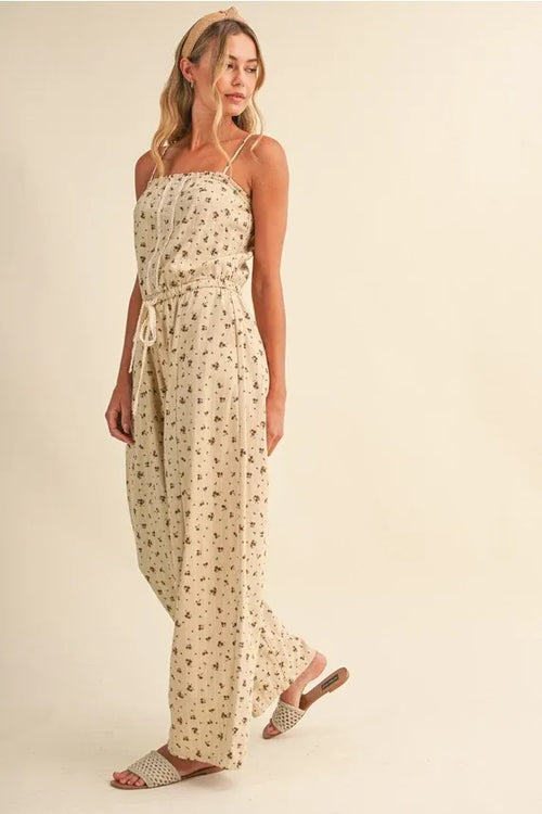 Beige ditsy floral sleeveless jumpsuit with thin spaghetti straps and drawstring waist featuring lace edge barrel design