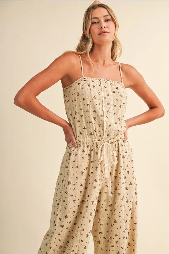 Beige ditsy floral sleeveless jumpsuit with lace edge, thin spaghetti straps, and a drawstring waist