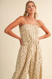 Beige ditsy floral sleeveless jumpsuit with lace edge, thin spaghetti straps, and a drawstring waist