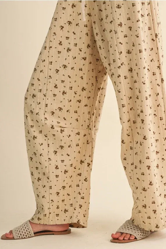 Beige ditsy floral wide-leg pants with subtle vertical ribbed texture and small brown flower pattern for floral sleeveless lace wear