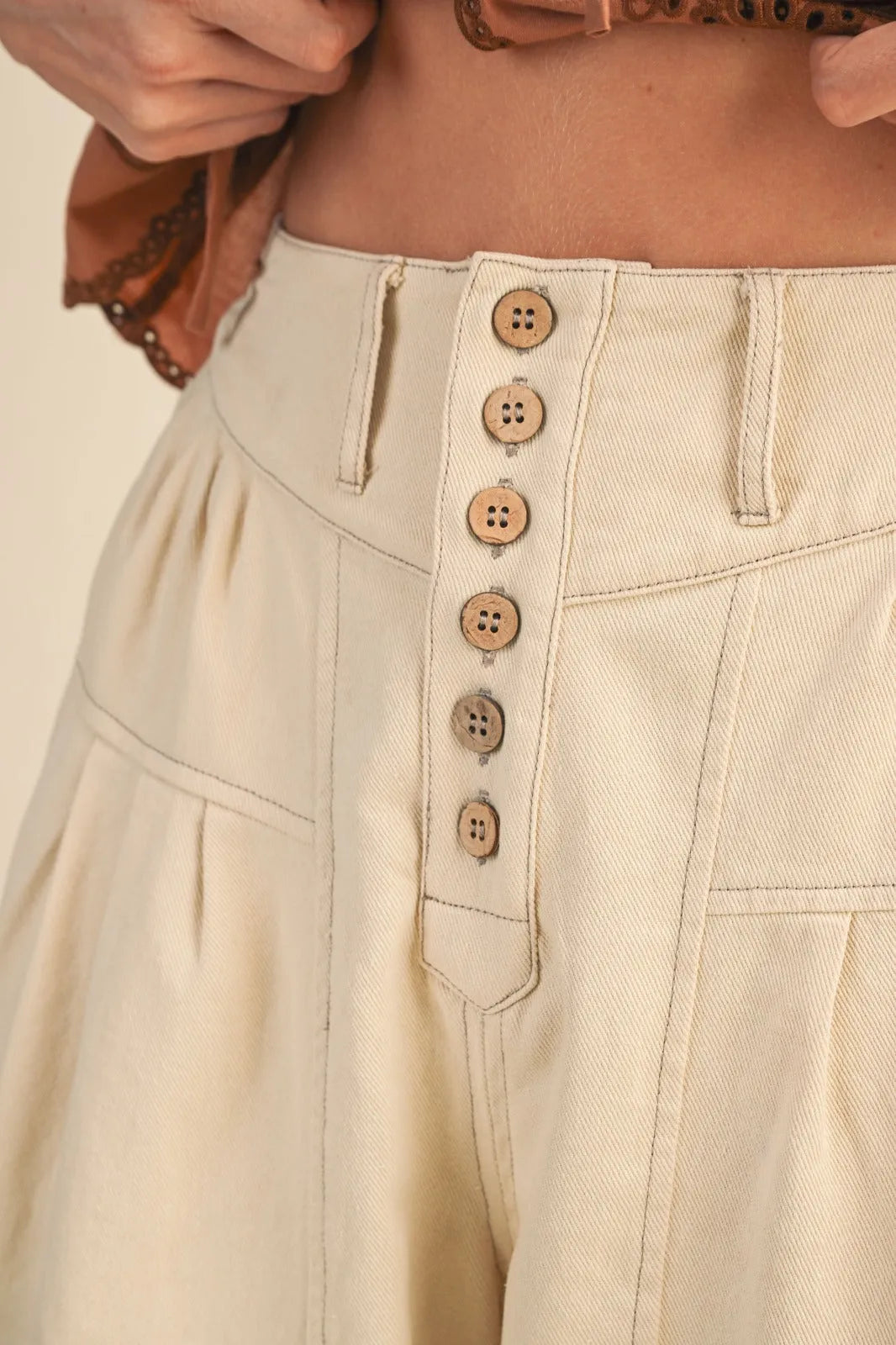 Beige high rise super wide leg crop denim trousers with button-front closure and matching wooden buttons