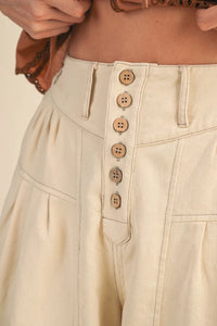 Beige high rise super wide leg crop denim trousers with button-front closure and matching wooden buttons