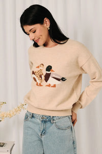 Beige knit sweater featuring a mallard duck graphic embroidered in natural tones on soft knit fabric