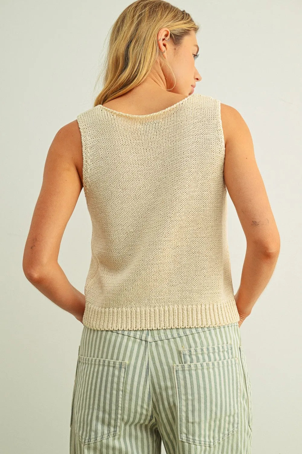 Beige sleeveless roundneck knitted top featuring a ribbed hem in soft knit material for versatile wear