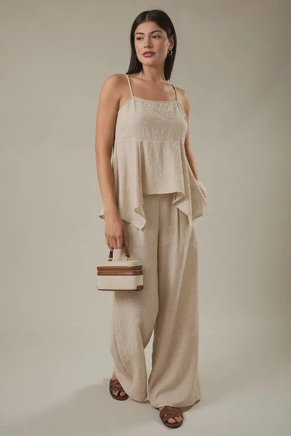 Beige linen top with delicate embroidery and flared asymmetrical hemline paired with wide leg pants