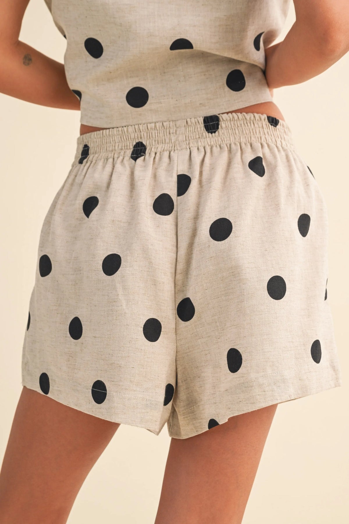 Beige polka dot linen shorts with an elastic waistband featuring black dots in a comfortable dot linen short design