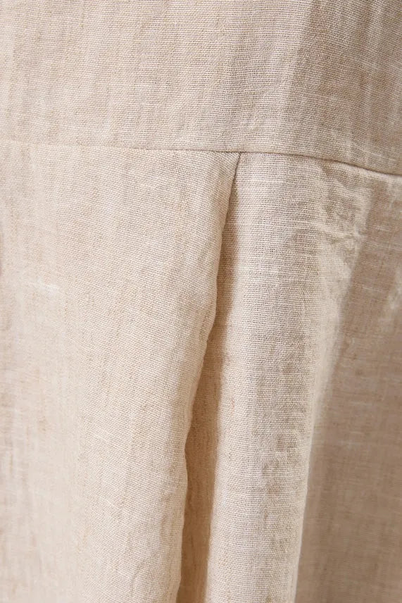 Beige linen skirt with subtle textured weave and soft pleats paired with sleeveless back smocking hanky hem top