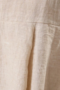 Beige linen skirt with subtle textured weave and soft pleats paired with sleeveless back smocking hanky hem top