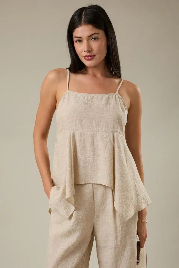 Beige linen sleeveless top with thin spaghetti straps featuring a smocking hanky hem detail