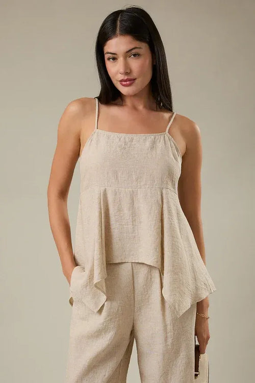 Beige linen sleeveless top with thin spaghetti straps featuring a smocking hanky hem detail