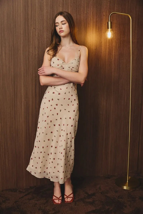A flowing beige floral midi dress with ruched bust and thin spaghetti straps for elegant occasions