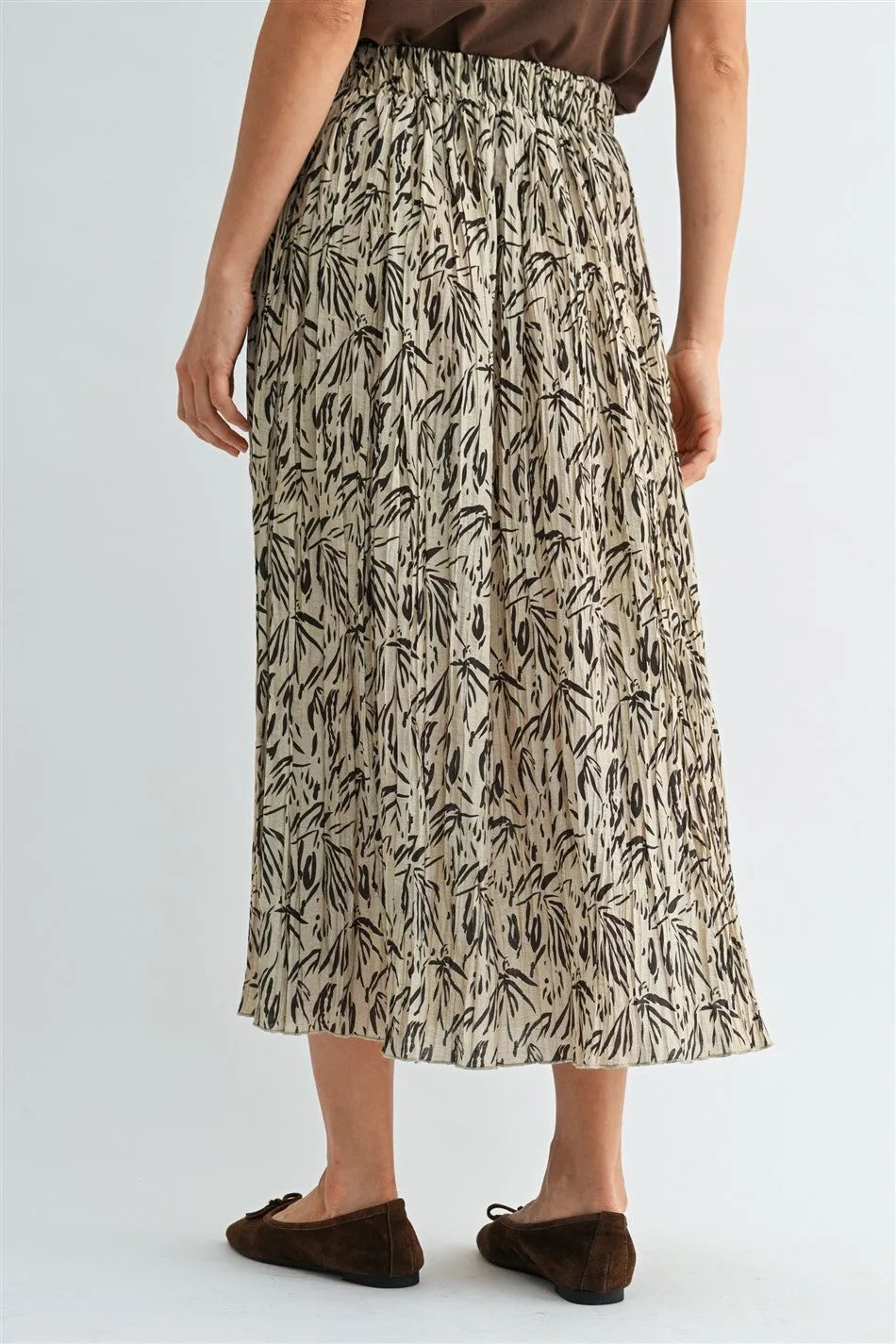 A flowing beige crinkle leaf print midi skirt with black leafy pattern and elastic waistband