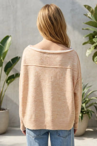 Beige off-the-shoulder knit sweater with soft textured fabric and ribbed cuffs featuring a contrast trim boat neck