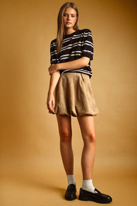 A beige pleated mini skirt made of soft textured fabric paired with a stripe pattern short sleeve knit top