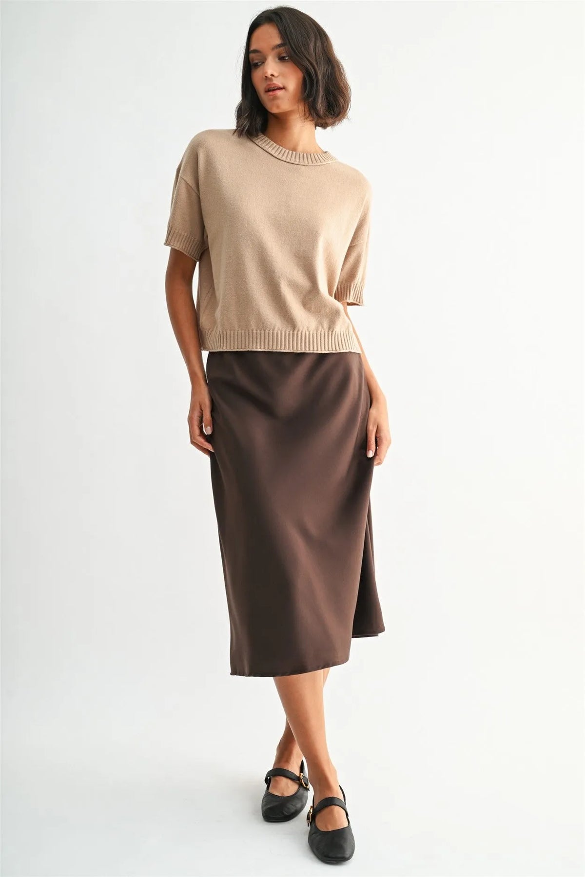 Beige short-sleeved crew neck crop knit top with ribbed neckline and cuffs paired with brown satin midi skirt