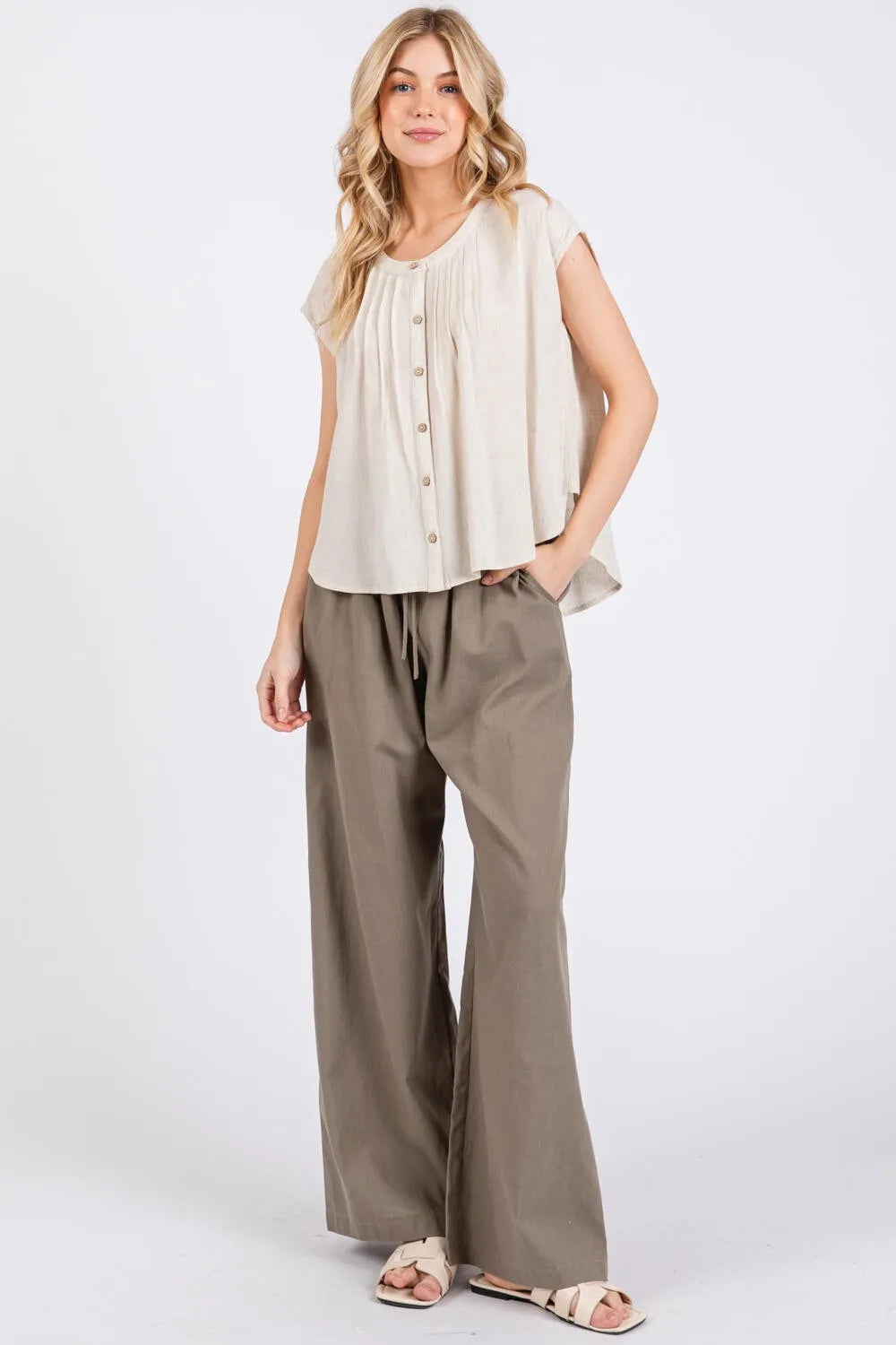 Beige sleeveless blouse with a relaxed flowing silhouette featuring pintuck detailed button design