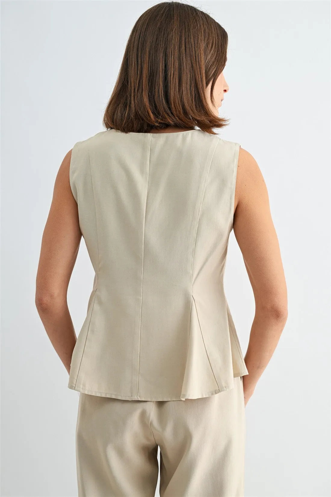 Beige sleeveless blouse with v neck peplum design featuring a structured back and subtle pleating for elegance