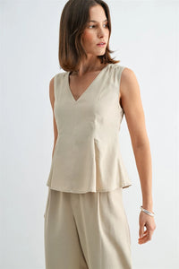 Beige v neck peplum sleeveless blouse with subtle hem pleating and fitted waist for a stylish look