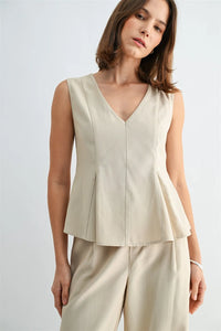 Beige v neck peplum sleeveless blouse with structured pleats offering a stylish and elegant look