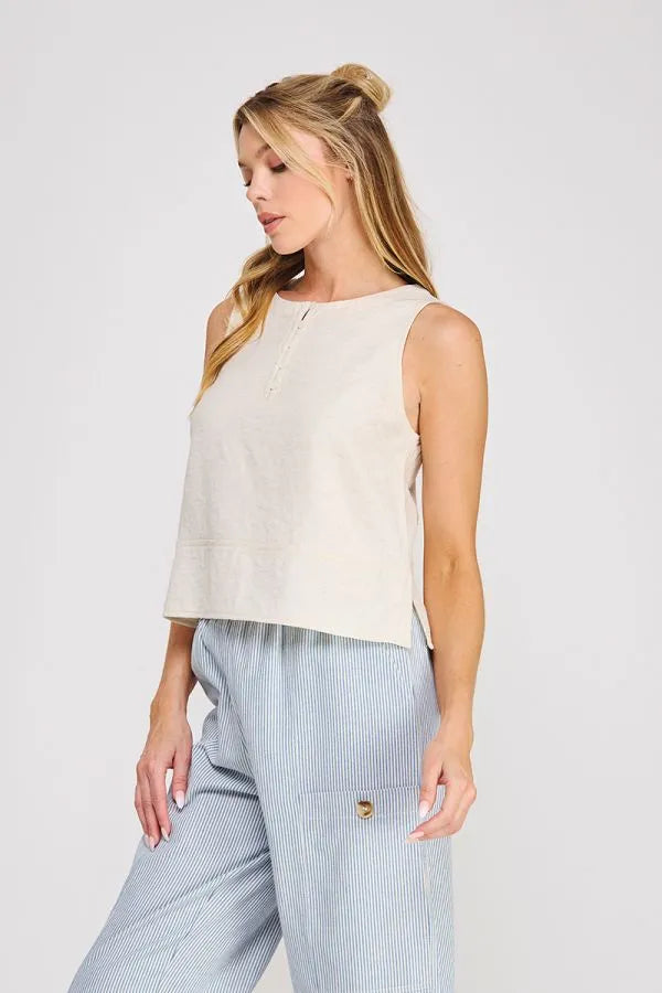 Beige linen button collar sleeveless top with subtle front zipper and side slits in textured fabric