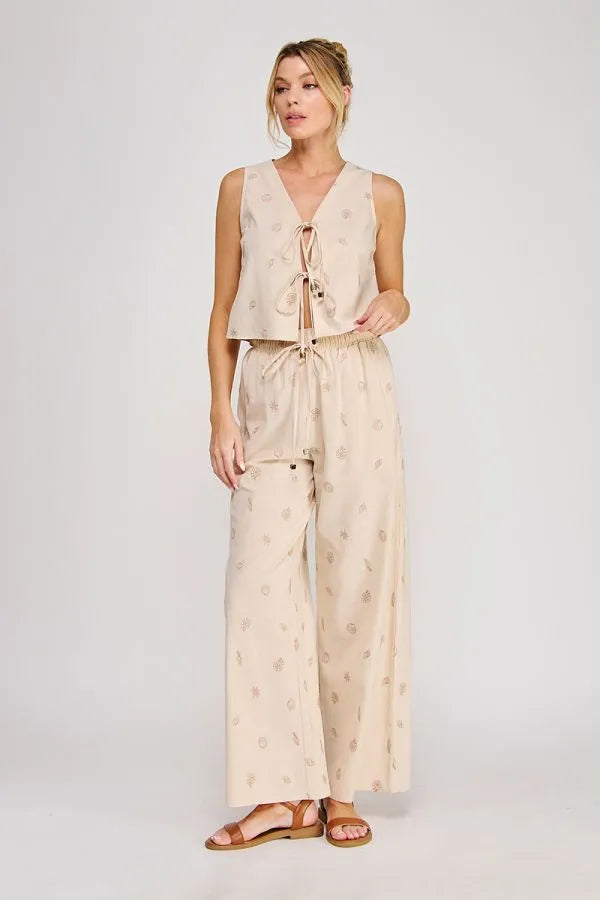 Beige seashell lace embroidered woven sleeveless top with v-neck and tie-front detail paired with patterned pants