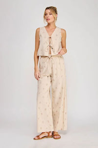 Beige seashell lace embroidered woven sleeveless top with v-neck and tie-front detail paired with patterned pants