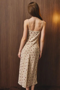 A beige floral midi dress with a ruched bust and thin spaghetti straps in a delicate slip dress style