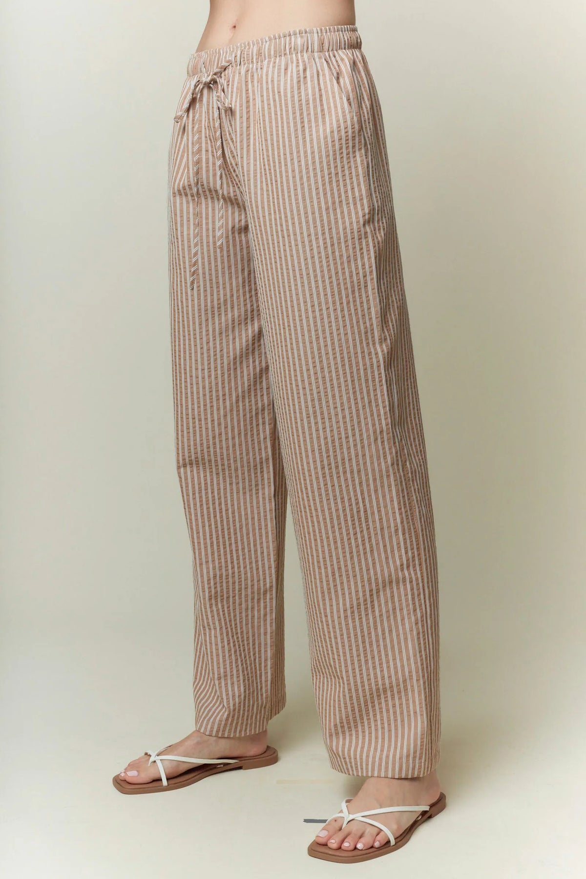 Beige and white yarn dye stripe elastic pants with wide-leg fit and drawstring waistband for comfortable wear