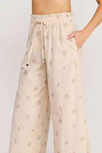 Beige wide-leg pants with seashell ruffle waist elastic tie and subtle gold-toned shell leaf pattern