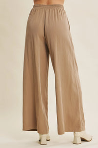 Beige wide leg pants with elastic waistband made from lightweight flowing fabric featuring a step washed look