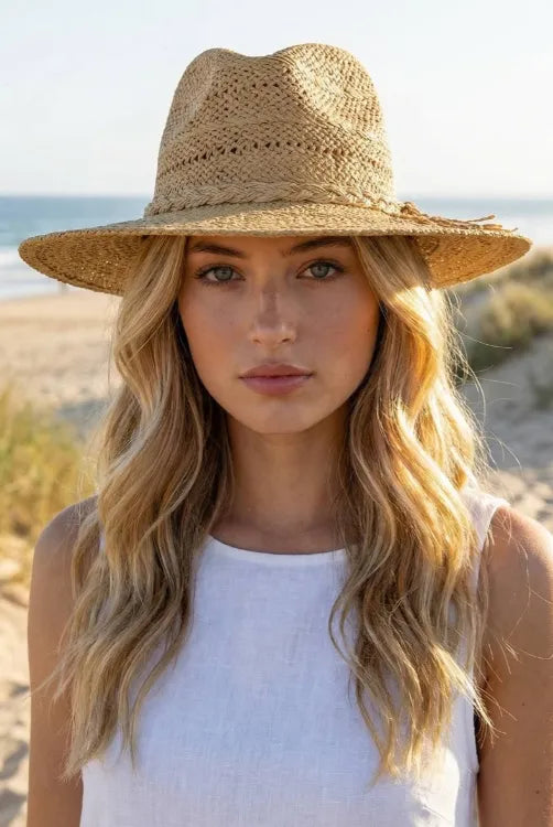 Beige woven straw fedora hat with wide brim and decorative fringe featuring a braided rope band detail